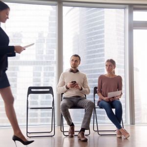 Happy hired woman walking in the room, got a job, being promoted to the post while her colleagues or other applicants looking at businesswoman with envy and hate, feeling winner and loser