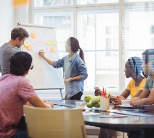 Business executives discussing with their colleagues on whiteboard during meeting at office