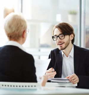 Young elegant applicant talking to employer and explaining some details of his previous job